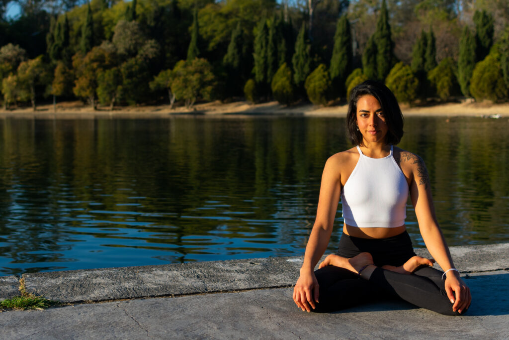 A woman meditating outdoors, prioritizing self-care and peace in her daily life.